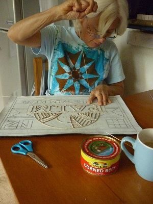 Artist Dame Robin White stitching on ngatu cloth