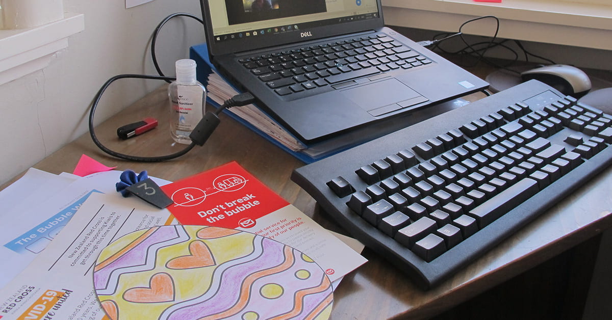 Open laptop on a desk with Covid-19 brochures set out next to it