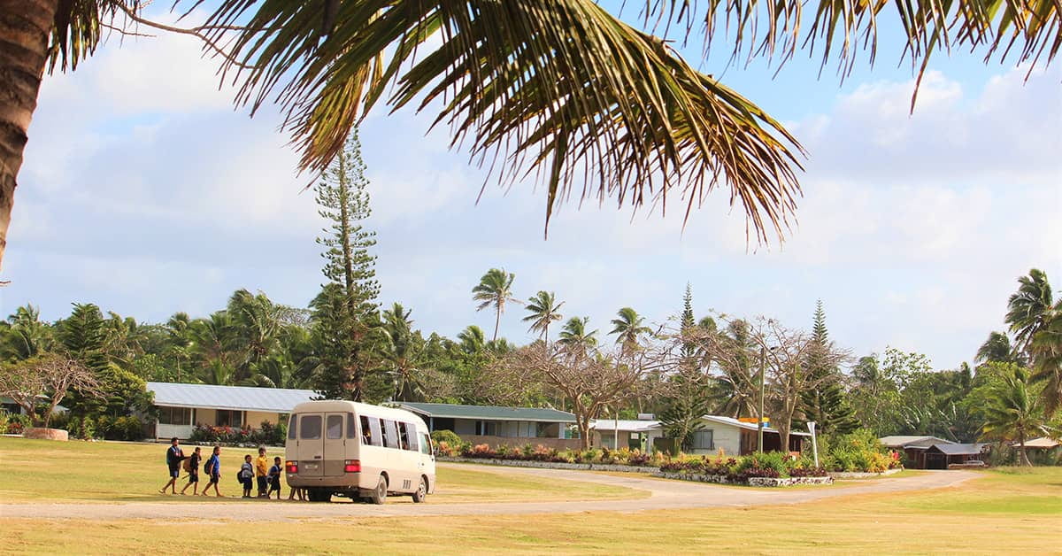 Children get on to a school bus in Hakupu, Niue