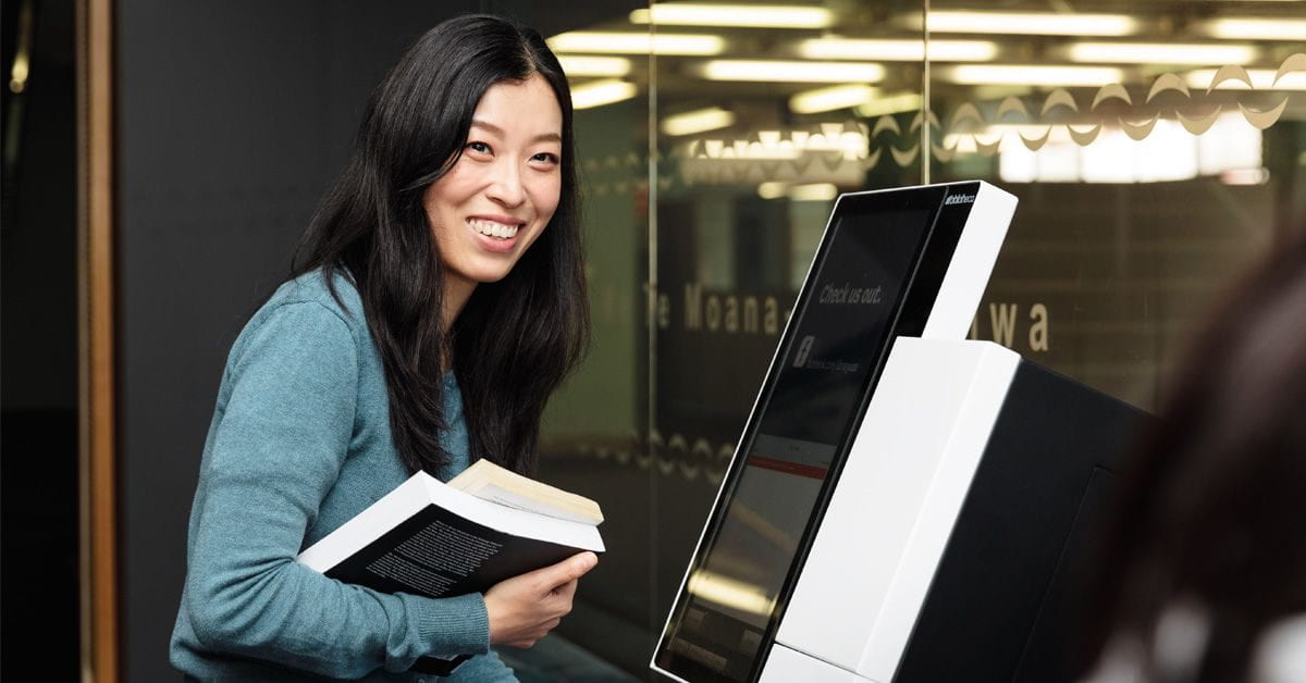 girl checking out books through self-service machine